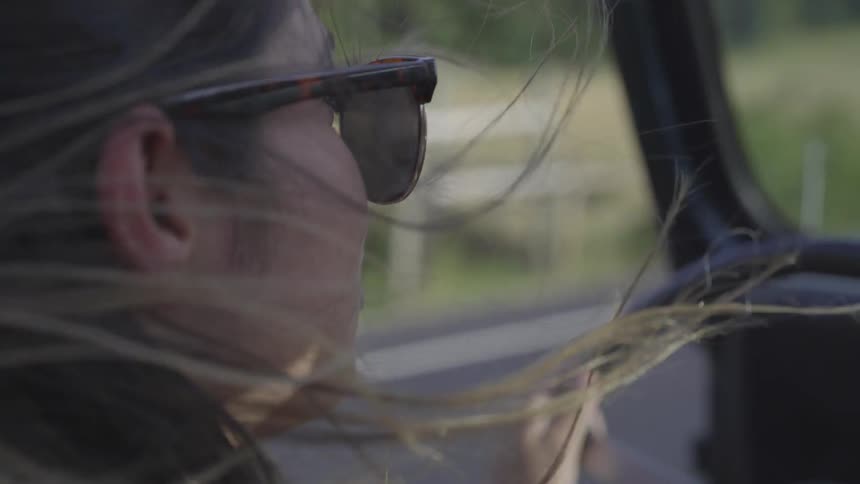 A woman driving with her hair flying around
