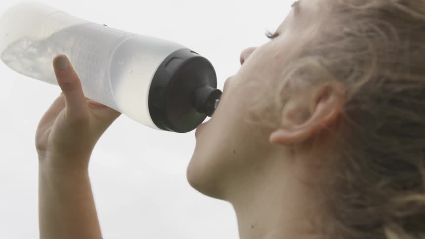 A woman drinks from a water bottle