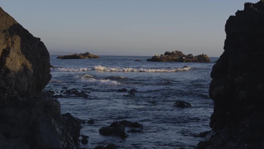 The ocean can be seen between two large cliffs