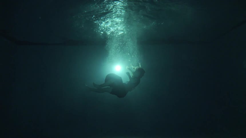 A woman plunges backwards into a dark pool