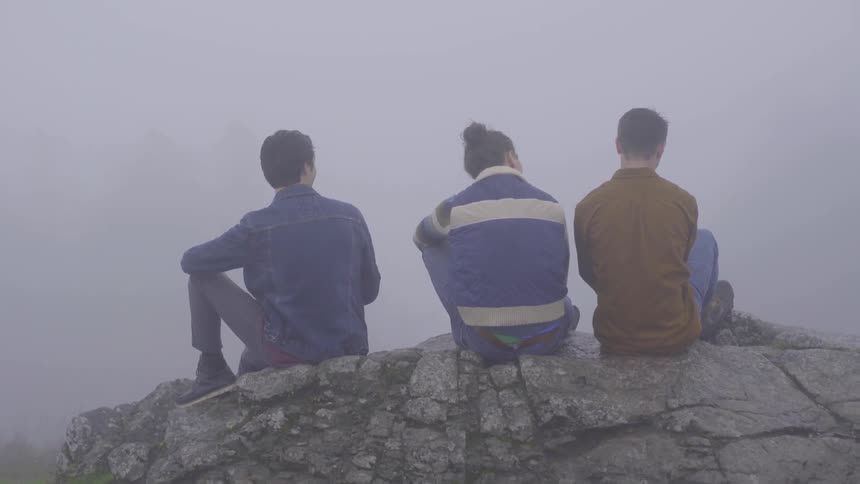 Three people sitting on a rock