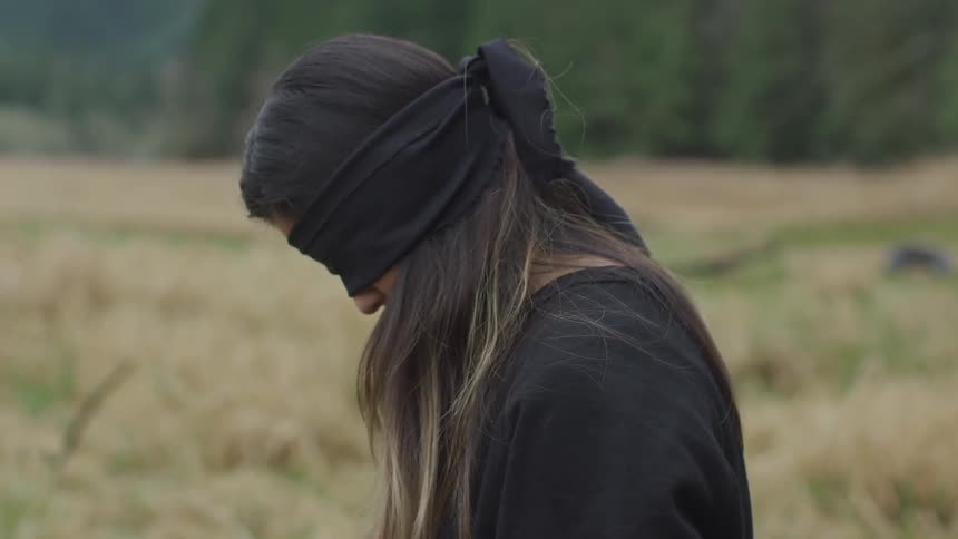 A woman blindfolded in a field