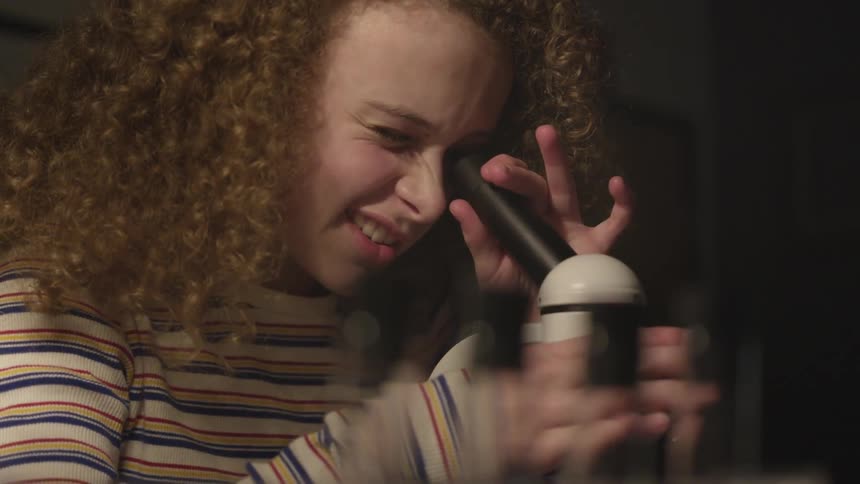 A little girl looks into a microscope as she adjusts the focus