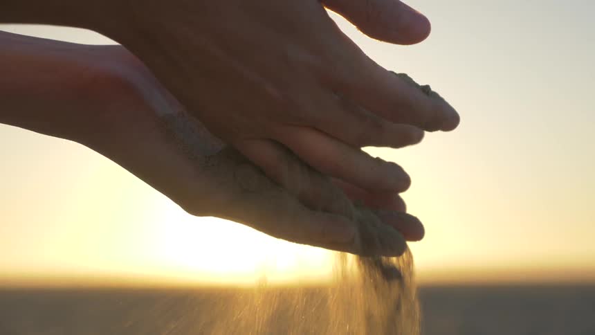 Sand falls softly through two hands