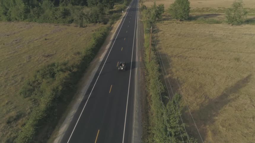 Lone car drives on a highway cutting through the plains