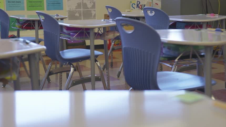 A kids classroom with small desks and blue chairs