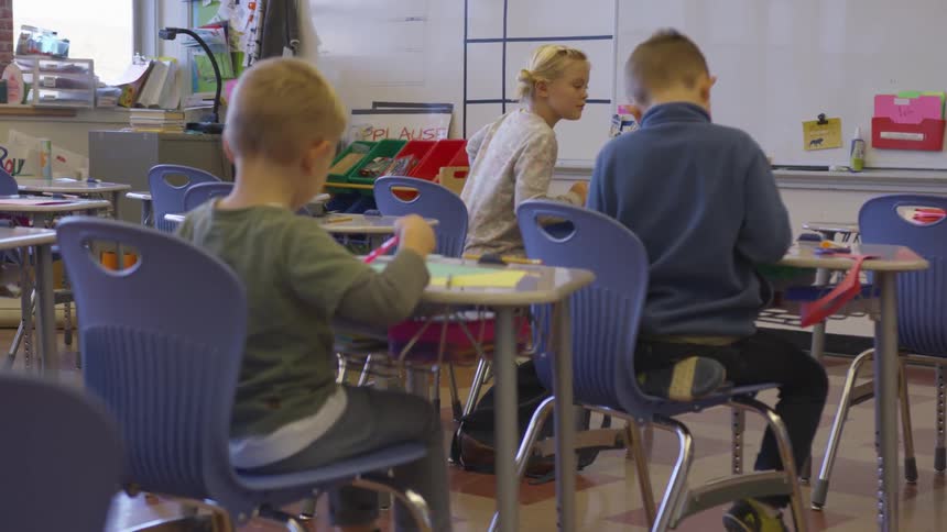 Children sit at desks in a school classroom