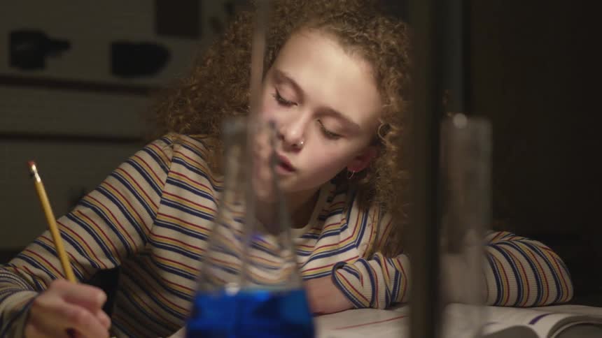 A little girl writes on paper with a pencil