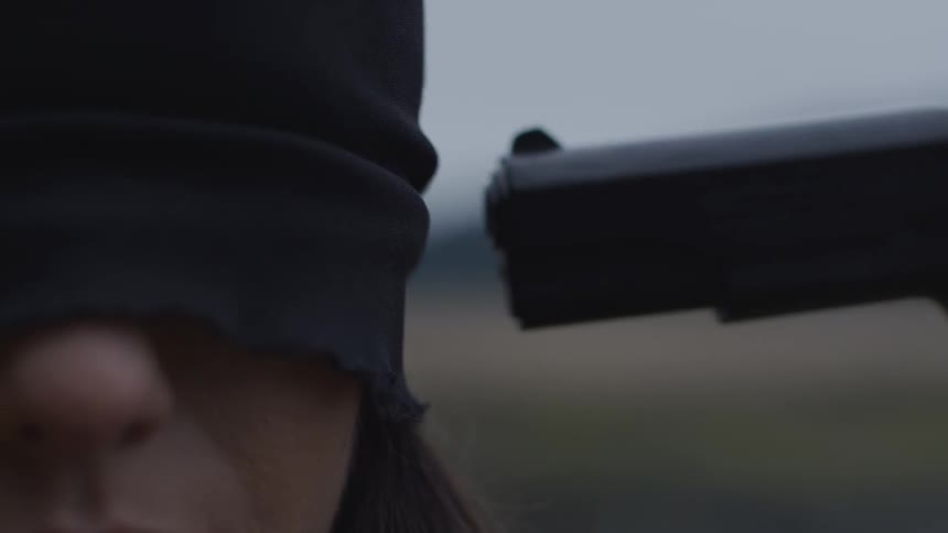 A gun is pointed to the head of a person blindfolded