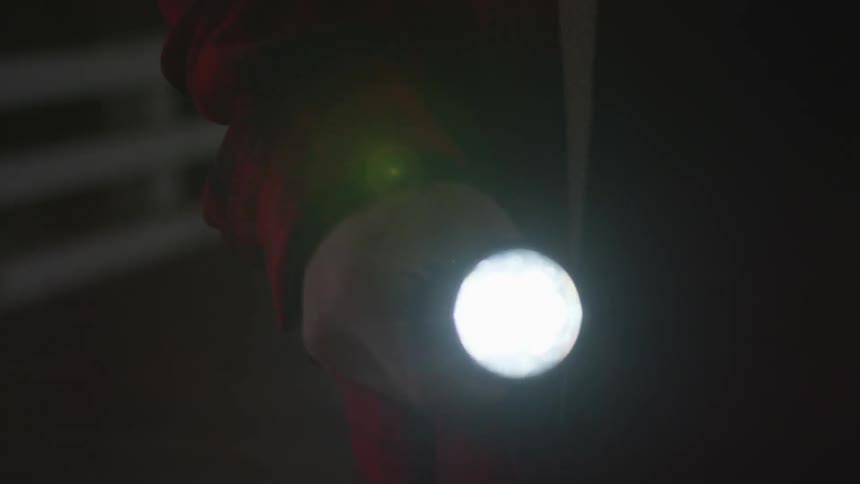A person holds a flashlight and waves it side to side