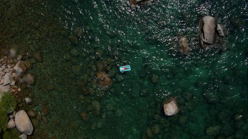 Woman lays on a blue floating raft in a large body of water