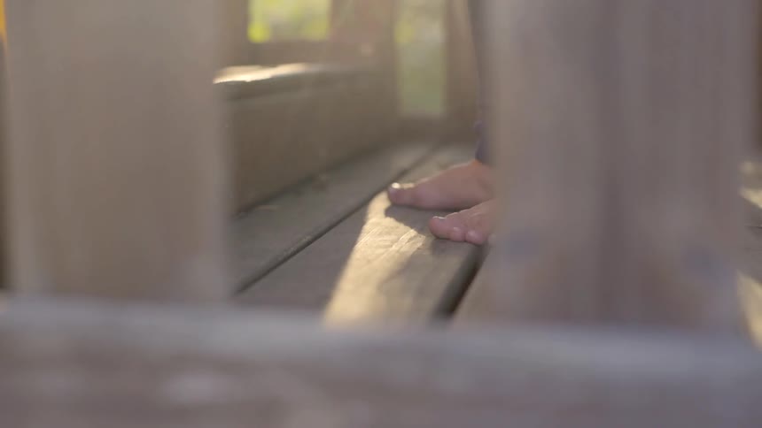 A person stands on a wooden deck in the sun