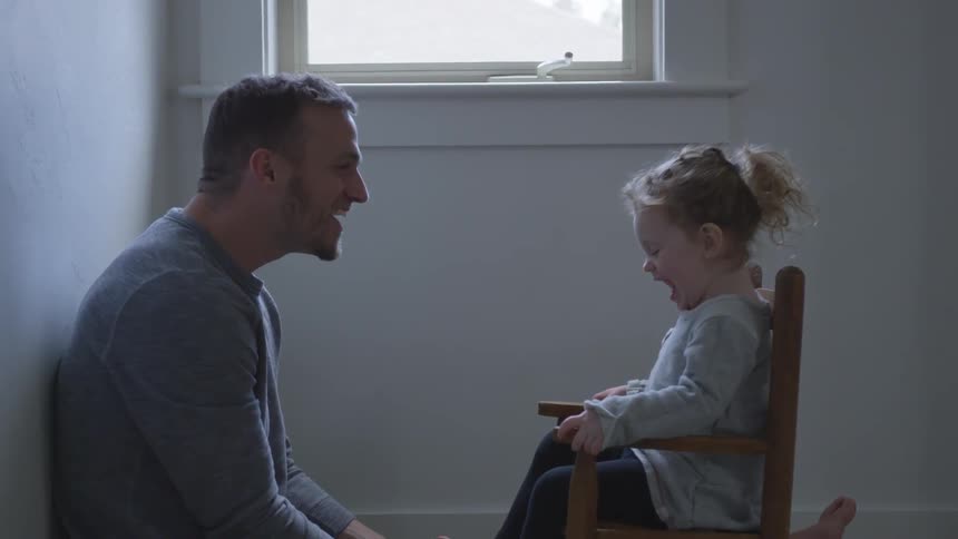 A man talking to his daughter in a rocking chair