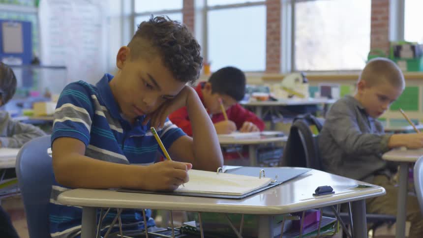 Boys work on problems in classroom lit by sunlight