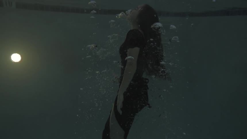 A woman in a dress swimming in a pool