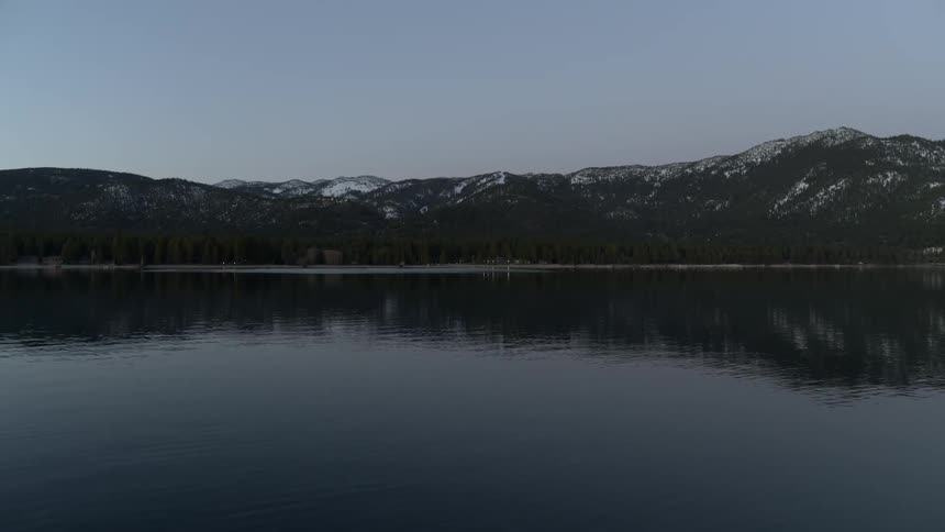 A river ripples alongside a tree covered mountain