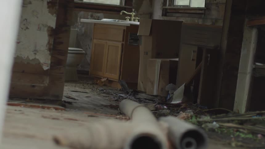 A dilapidated destroyed house has debris all over the floor