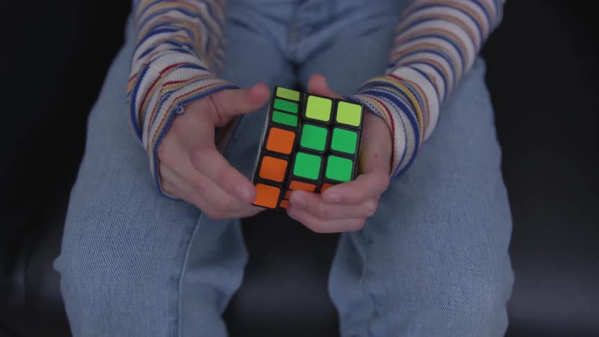A young person works on solving a rubik's cube