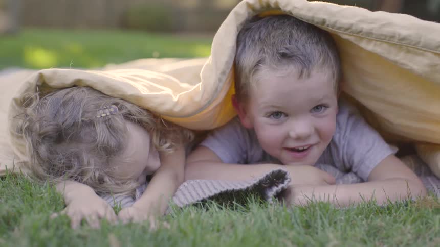 Kids laying on a blanket in a field
