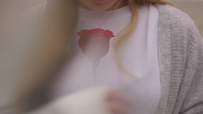 A woman is holding a rose