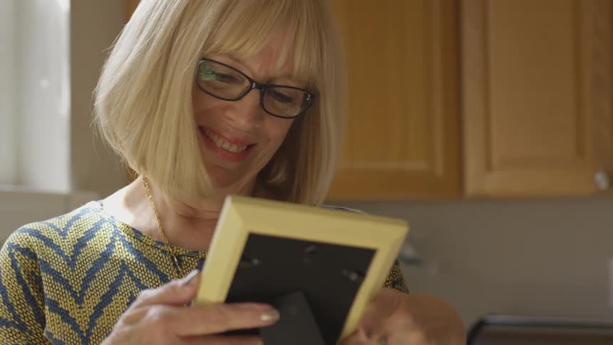 Elderly woman looks at photograph in frame