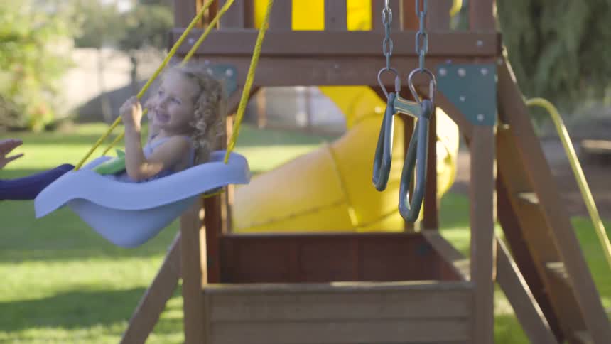 Young girl laughs as she swings on a swing