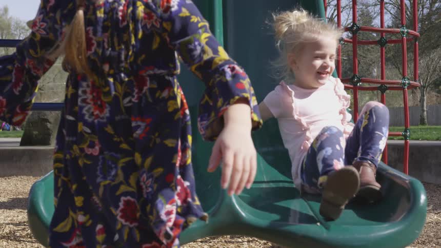 Two girls slide down a playground slide