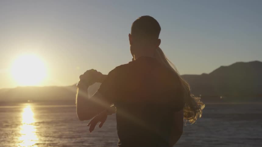 Man and woman dancing on desert at sunset