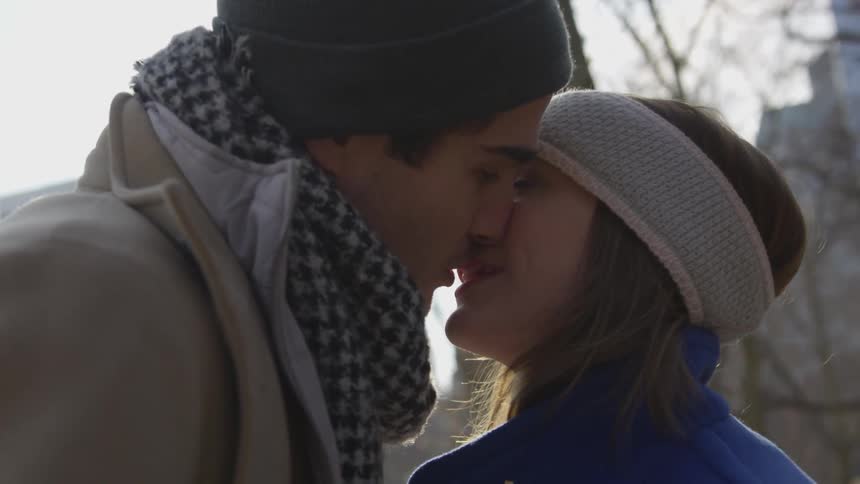 A man and woman kiss outside on a cold day