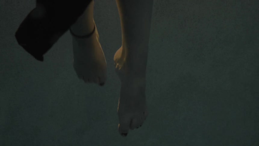A woman kicks her feet in the water as she wears a dress