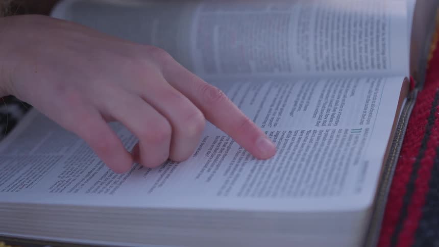 Hand following words through a book