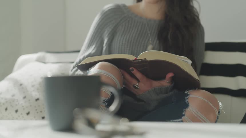 Woman sits on couch reading