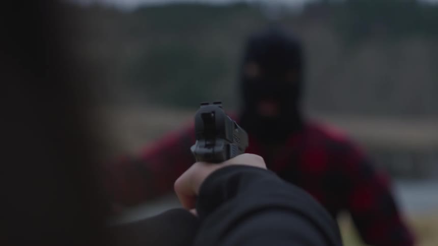 Someone shooting a gun at a man wearing a ski mask