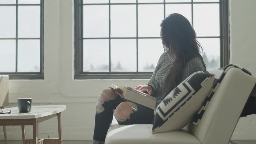 Woman sits on couch reading