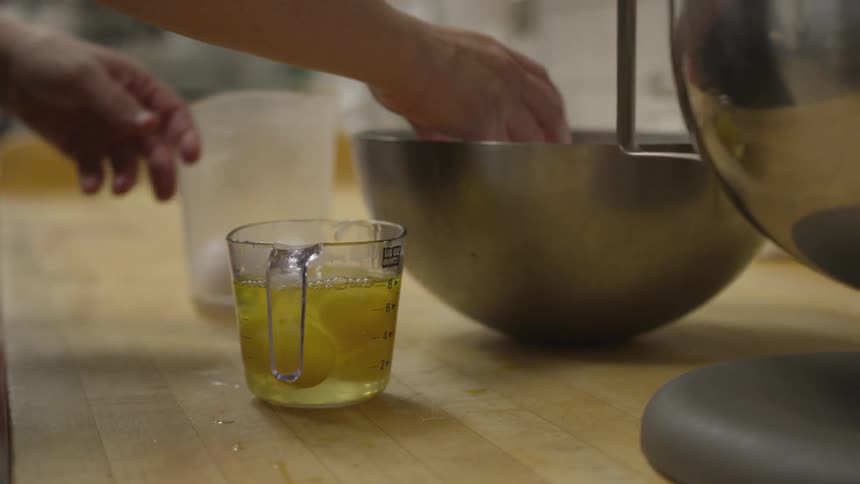 Person breaking an egg into a measuring cup