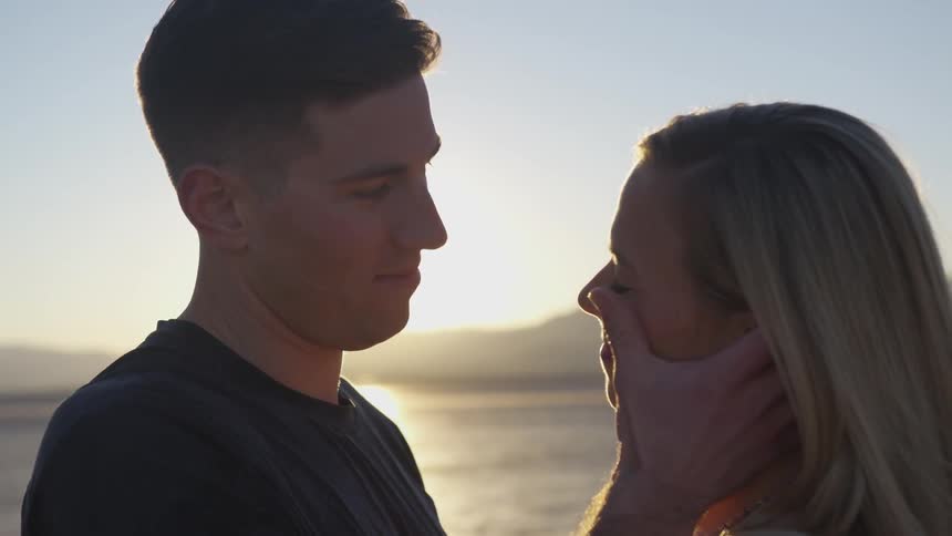 Man strokes woman's cheek in desert at sunset