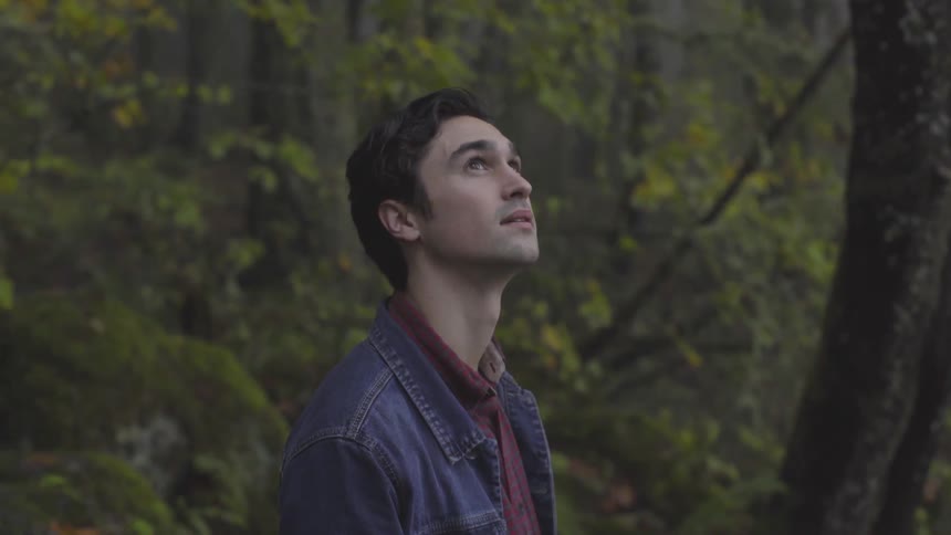 Man in forest looks up and smiles