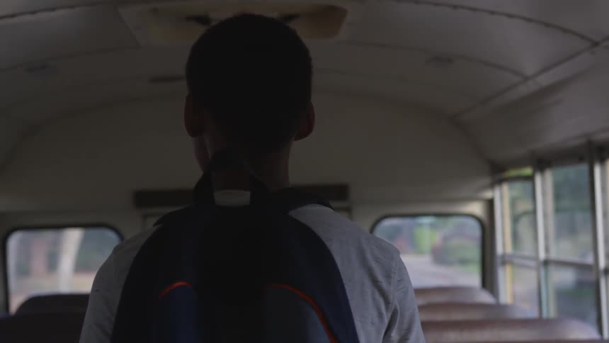 A young boy walks in the school bus