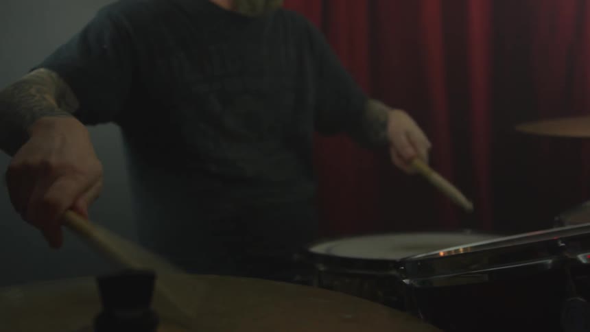 Man drums in a dark studio