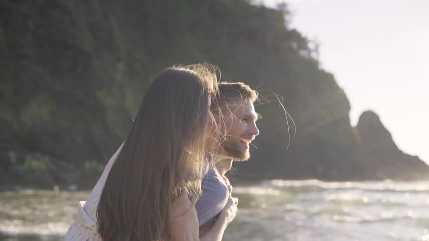 A man is holding a woman near the beach