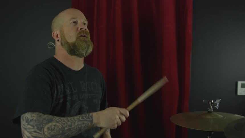 A man hits drum sticks together in the air