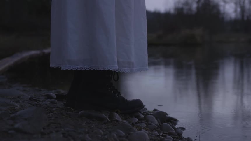 A woman standing at the edge of a lake