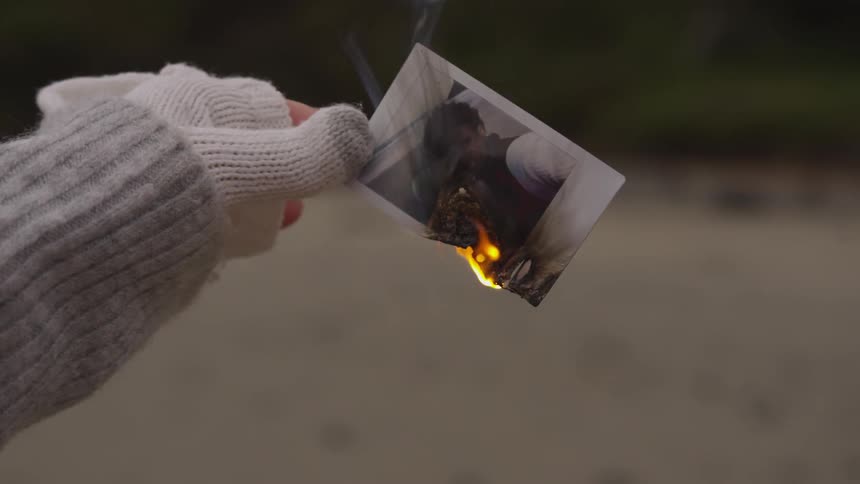 A picture burns slowly in a person's hand