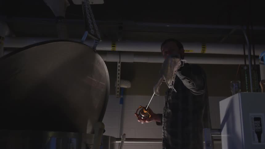 Man wiping clean a large metal rod in a commercial building