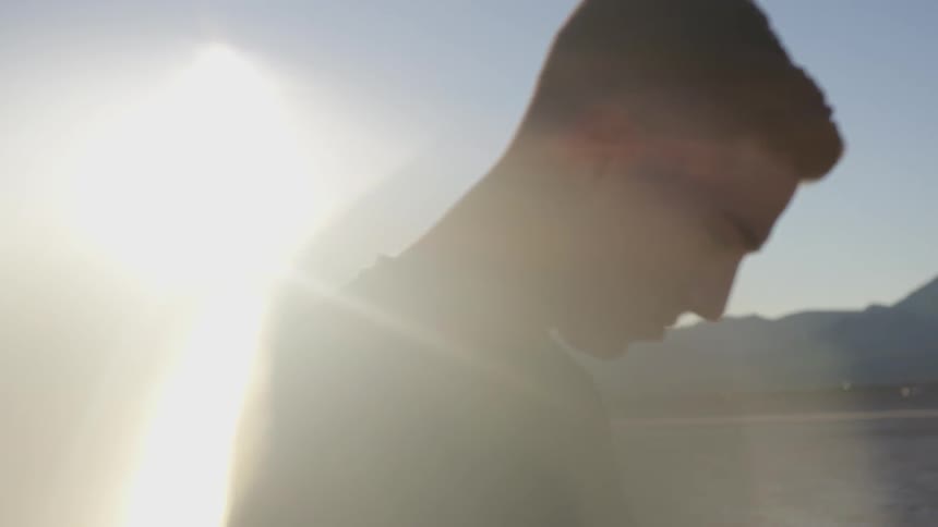 A man standing in a sunny desert and looking down