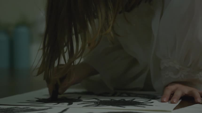 A child scribbles with a black crayon