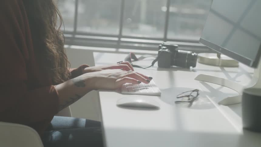 A woman is typing on a computer keyboard