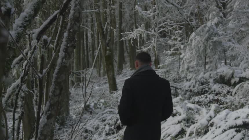 A man walks through a snow covered forest