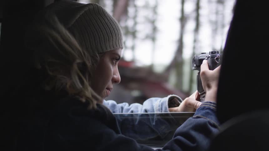 A woman taking photos out of a car window