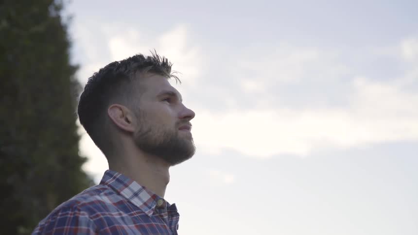 A man standing outdoors looking up at the sky during the day